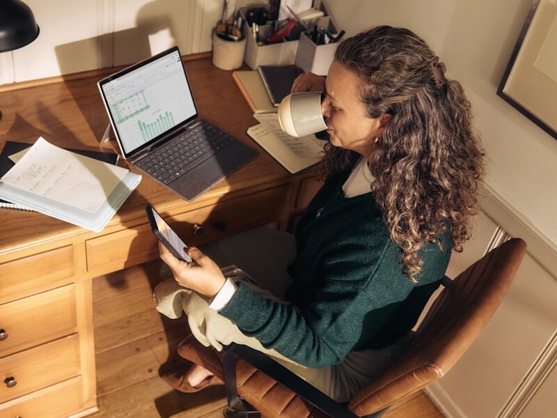 Woman working at a desk with laptop and tablet.